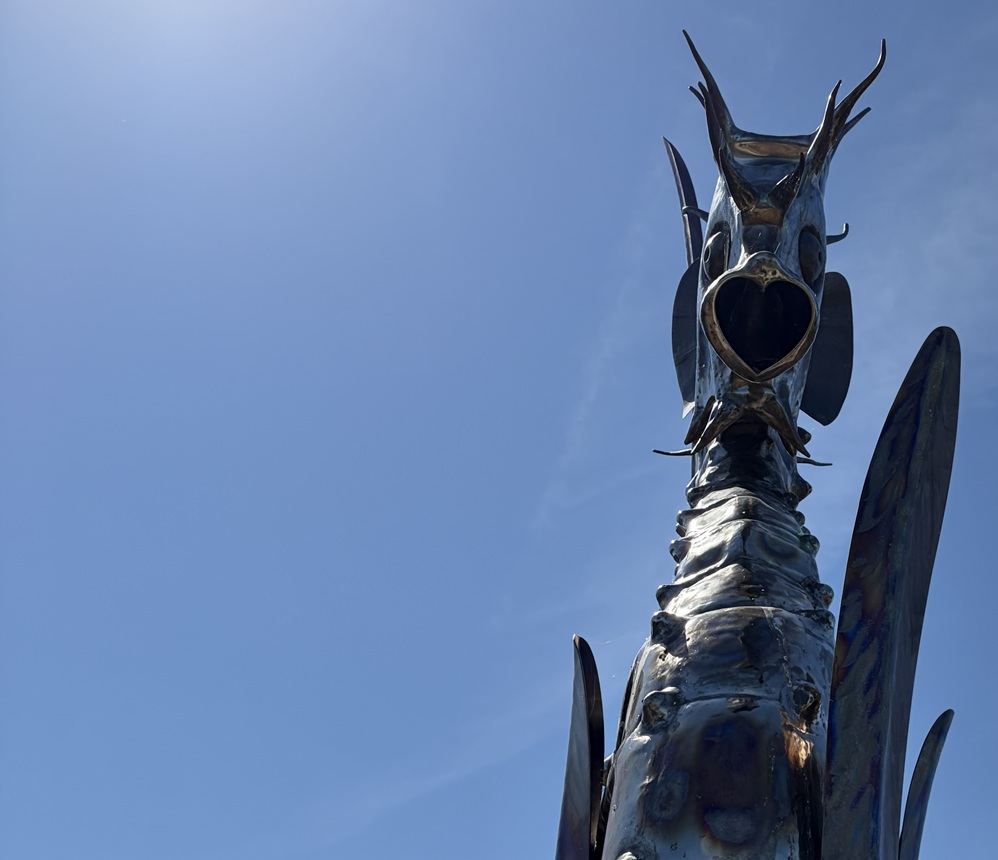 metal dragon with heart shaped mouth against nice blue sky